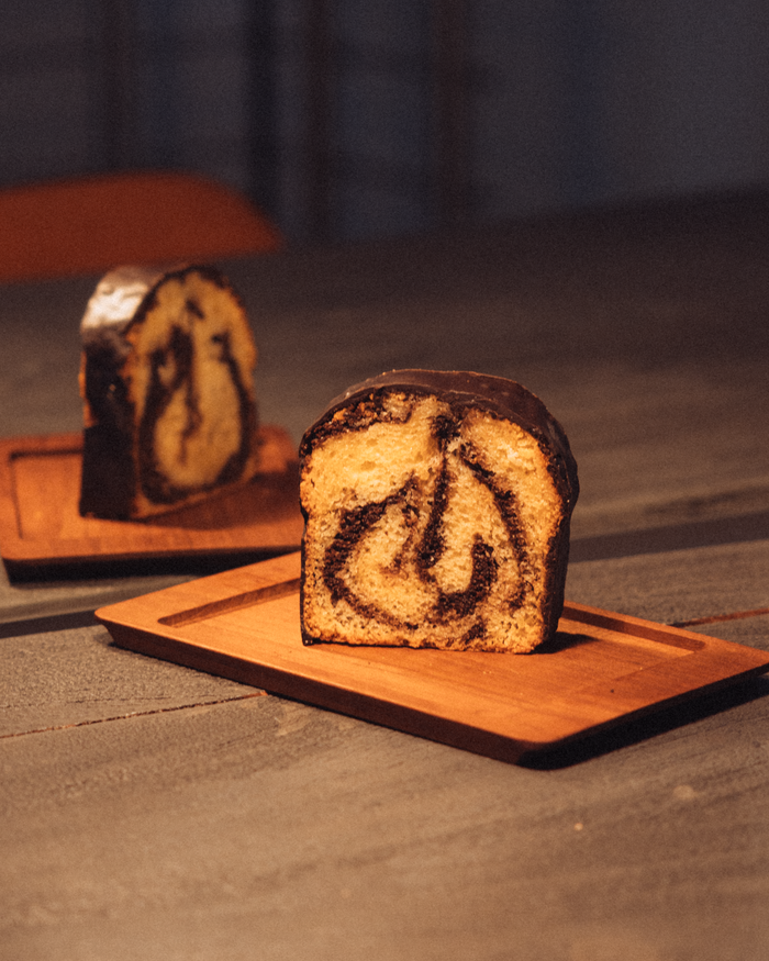 A mouthwatering slice of marble cake on a wooden tray, perfect for dessert lovers.