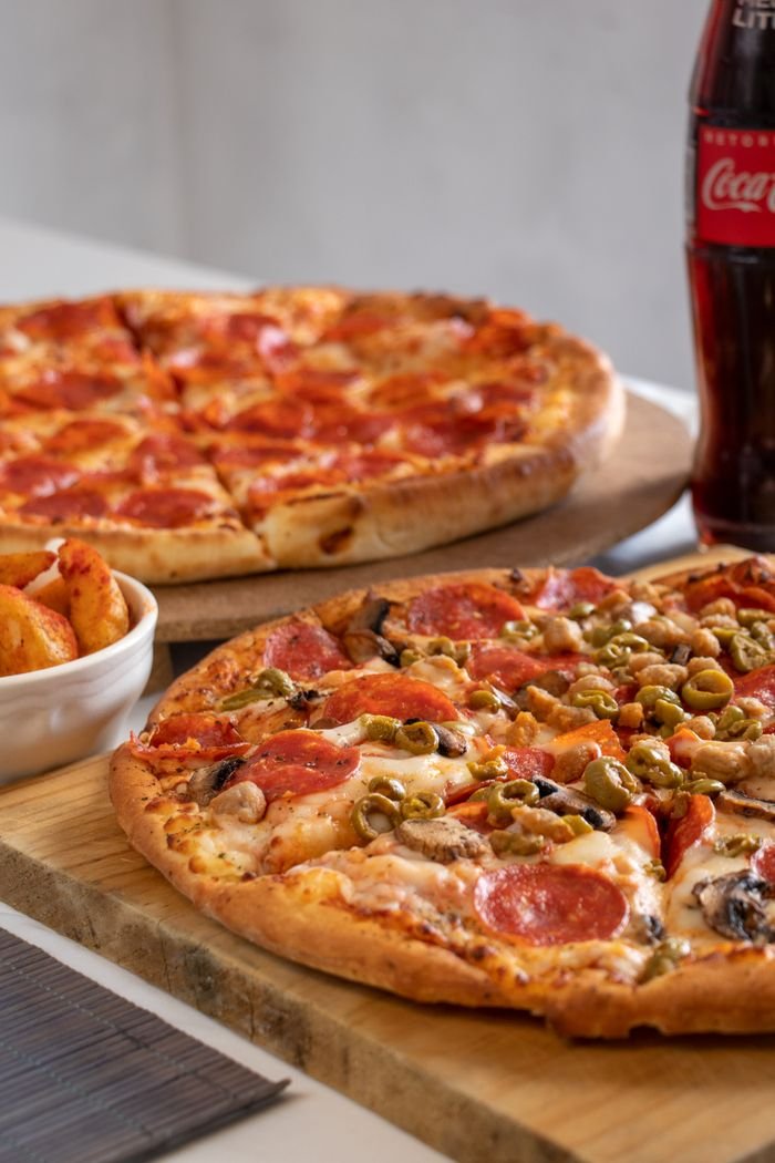 Close-up of pepperoni and veggie pizzas with soda, perfect for a casual dining experience.
