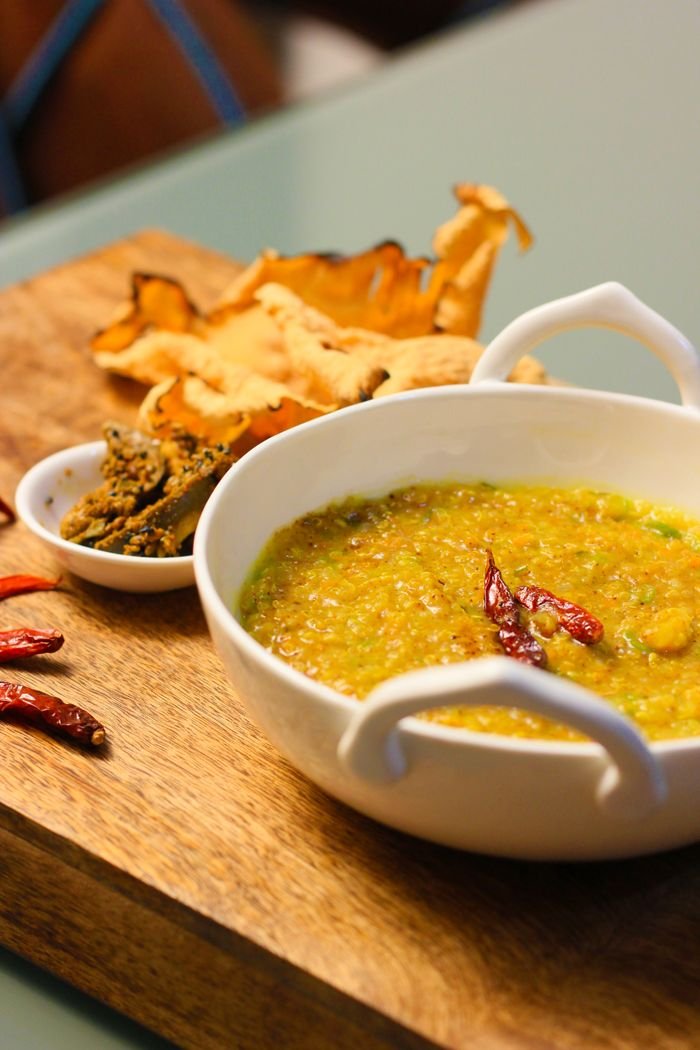 Mouth-watering khichdi served with crispy chilies and papadum on a wooden board.
